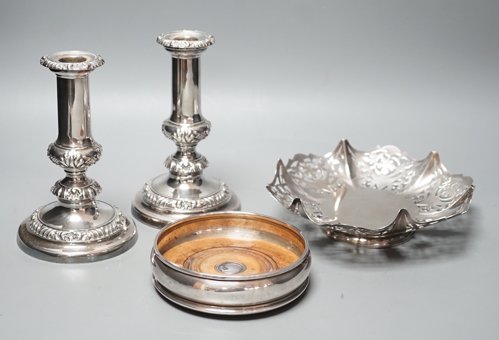 A modern silver mounted wine coaster, London, 1996, diameter 12.4cm, an earlier pierced silver bonbon dish and a pair of plated candlesticks.